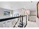 Bright upstairs hallway with white carpet, black-and-white bannister, pendant light, and view of the entryway at 5297 Mill Stream Dr, St Cloud, FL 34771
