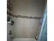 Close up of shower with tile surround, a shower caddy and updated hardware at 815 S Solandra Dr, Orlando, FL 32807