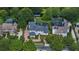 Stunning aerial of white two-story home with manicured lawn, bordered by mature trees, pool and a waterside gazebo at 10849 Emerald Chase Dr, Orlando, FL 32836