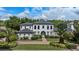 Stately white two-story home with lush landscaping, paver driveway, and mature palm trees creates a tropical ambiance at 10849 Emerald Chase Dr, Orlando, FL 32836