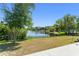 Landscaped backyard offering a serene lake view with a black fence and mature trees at 1103 Lindley Cove Cir, Deland, FL 32724