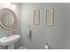 Half bath features a stylish pedestal sink, elegant mirror, and decorative wall accents at 1103 Lindley Cove Cir, Deland, FL 32724