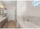 Bright bathroom features a soaking tub, double vanity with marble counters and tile surround at 1103 Lindley Cove Cir, Deland, FL 32724