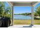 Covered patio view of a lake with a black fence and lush trees under a clear blue sky at 1103 Lindley Cove Cir, Deland, FL 32724