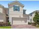 Exterior elevation of a townhome featuring a two-car garage and brick driveway at 1168 Lakeshore Breeze Pl, Kissimmee, FL 34747