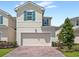 Two-story home featuring a two-car garage, brick paver driveway, and manicured landscaping at 1168 Lakeshore Breeze Pl, Kissimmee, FL 34747
