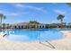 Large community pool surrounded by palm trees and a nearby clubhouse with ample seating and shade at 15186 Book Club Rd, Winter Garden, FL 34787