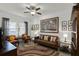 Comfortable living room featuring a leather sofa, armchairs, and a large art piece on the wall at 15186 Book Club Rd, Winter Garden, FL 34787