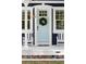 Close-up of a light blue front door adorned with a green wreath, flanked by white rocking chairs at 1521 E Harwood St, Orlando, FL 32803
