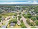 A sweeping aerial view captures the vibrant community with a charming home and nearby lake under a sunny, partly cloudy sky at 1961 Lochshyre Loop, Ocoee, FL 34761
