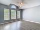 Bright bedroom featuring three large windows, a ceiling fan, neutral paint and modern wood-look flooring at 1961 Lochshyre Loop, Ocoee, FL 34761