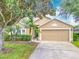 Charming single-story home featuring a well-manicured lawn, mature tree, and a two-car garage at 1961 Lochshyre Loop, Ocoee, FL 34761