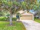 Inviting single-story home with lush landscaping, mature trees, and a two-car garage on a sunny day at 1961 Lochshyre Loop, Ocoee, FL 34761