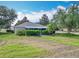 Well-kept front yard showcasing a cozy one-story home with tidy landscaping and mature trees under a partly cloudy sky at 1961 Lochshyre Loop, Ocoee, FL 34761