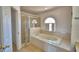 Bathroom featuring a jetted tub, tiled surround, and a glass-enclosed shower at 2209 Pecos Ct, Poinciana, FL 34759