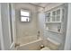 Full bathroom with white tiled walls, a window above the tub, and a storage cabinet above the toilet at 2209 Pecos Ct, Poinciana, FL 34759