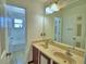Bathroom with a double sink vanity with a large mirror and view of the shower/tub in the adjacent room at 2209 Pecos Ct, Poinciana, FL 34759