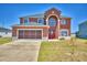 Inviting two-story home featuring a screened two car garage, arched entryway, and red front door at 2209 Pecos Ct, Poinciana, FL 34759