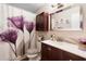 Bathroom features a decorative floral shower curtain, wood vanity, white marble countertop, and decorative mirror at 2645 Debany Rd, Kissimmee, FL 34744