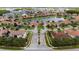 An aerial perspective showcasing a well-planned neighborhood with lush landscaping, tile-roofed homes, and community entrance at 2721 Swoop Cir, Kissimmee, FL 34741