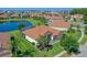Aerial view of a home with a screened patio, beautiful landscaping, and a tile roof near a lake at 2721 Swoop Cir, Kissimmee, FL 34741