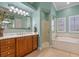 Bright bathroom featuring a shower, tub, wood cabinet vanity with a large mirror, with light-toned walls and flooring at 2721 Swoop Cir, Kissimmee, FL 34741