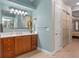 Bright bathroom featuring sliding door closet, wood cabinet vanity with a large mirror, and light-toned walls and flooring at 2721 Swoop Cir, Kissimmee, FL 34741