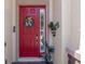 Vibrant red front door decorated with a wreath, complemented by potted plants and stucco walls at 2721 Swoop Cir, Kissimmee, FL 34741
