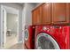 Well-equipped laundry room featuring a red washer and dryer set, complemented by abundant wooden cabinet storage at 2721 Swoop Cir, Kissimmee, FL 34741