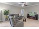 Comfortable living room features a large gray sectional, ceiling fan, and tile flooring at 2721 Swoop Cir, Kissimmee, FL 34741