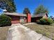 Cozy home featuring a red exterior with stone accents, attached garage, and mature landscaping at 2813 Calico Ct, Orlando, FL 32822
