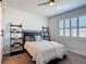 Cozy bedroom featuring a ceiling fan, comfortable queen bed, plantation shutters, and stylish ladder shelves at 308 Buchannan Dr, Davenport, FL 33837
