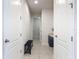 Hallway with neutral tile flooring, white walls, doors, black bench, and hall tree with storage at 308 Buchannan Dr, Davenport, FL 33837