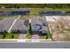Aerial view of two homes with brick driveways, manicured lawns, solar panels, and a pond in the background at 3134 Viceroy Ct, Poinciana, FL 34759