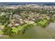 Aerial view of a lakefront community featuring multiple brown roofed buildings, lush trees, and a serene lake at 420 Forestway Cir # 108, Altamonte Springs, FL 32701
