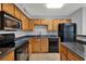 Modern kitchen featuring wood cabinetry, granite counters, and black appliances at 420 Forestway Cir # 108, Altamonte Springs, FL 32701
