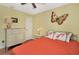 Comfortable bedroom with orange quilted bedspread and butterfly wall decor at 4833 Palm Tree Ct, Windermere, FL 34786
