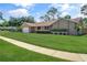 Well-manicured front yard with lush green grass and trimmed bushes, leading to a charming tan single-story home at 4833 Palm Tree Ct, Windermere, FL 34786
