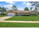 Well-maintained front yard with manicured lawn leading to a tan single-story home with an attached two-car garage at 4833 Palm Tree Ct, Windermere, FL 34786