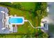 Aerial view of property featuring a pool, lush lawn, mature trees, dock, and boat lift at 570 Manor Rd, Maitland, FL 32751