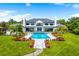 Lush backyard with large pool, spa, mature trees, and verdant lawn leads up to stately home at 570 Manor Rd, Maitland, FL 32751