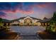 Breathtaking exterior view of estate home with paved driveway, tile roof, manicured landscaping and a colorful sunset sky at 570 Manor Rd, Maitland, FL 32751