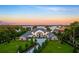 Stunning lakefront estate with lush landscaping, circular driveway, and stone accents under a colorful sunset sky at 570 Manor Rd, Maitland, FL 32751