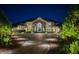 Nighttime view of an elegant luxury home exterior showcasing professional landscaping, and an arched entryway at 570 Manor Rd, Maitland, FL 32751