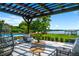 Outdoor seating area under a pergola with a view of the pool, landscaped yard, and waterfront gazebo at 570 Manor Rd, Maitland, FL 32751