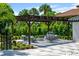 An inviting outdoor seating area beneath a wooden pergola, surrounded by lush greenery and manicured landscaping at 570 Manor Rd, Maitland, FL 32751