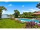 A serene pool and lakefront property featuring a gazebo, lush lawn, and vibrant flower beds at 570 Manor Rd, Maitland, FL 32751