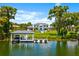 Lakefront property including a boat dock, jet skis, lush grass, mature landscaping, and well-manicured lawn at 570 Manor Rd, Maitland, FL 32751