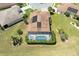 Aerial view of a home with a screened-in pool, solar panels, and manicured landscaping at 5799 Linen Bluff Pl, Leesburg, FL 34748
