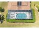 Aerial view of a private screened-in pool with sun loungers, surrounded by lush landscaping at 5799 Linen Bluff Pl, Leesburg, FL 34748